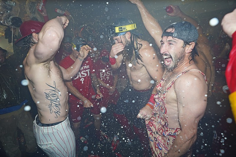 Sep 23, 2024; Philadelphia, Pennsylvania, USA; Philadelphia Phillies first baseman Bryce Harper (3), outfielder Brandon Marsh (16) and catcher Garrett Stubbs (21) celebrate the National League East Division title in the locker room after defeating the Chicago Cubsat Citizens Bank Park. Mandatory Credit: Eric Hartline-Imagn Images