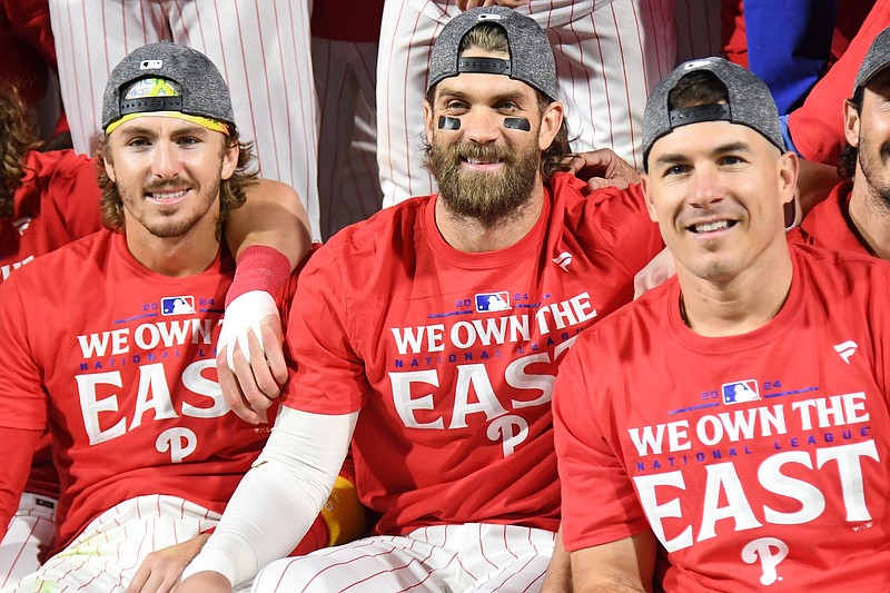 Sep 23, 2024; Philadelphia, Pennsylvania, USA; Philadelphia Phillies second base Bryson Stott (5), first baseman Bryce Harper (3) and catcher J.T. Realmuto (10) celebrate the National League East Division title after defeating the Chicago Cubsat Citizens Bank Park. Mandatory Credit: Eric Hartline-Imagn Images