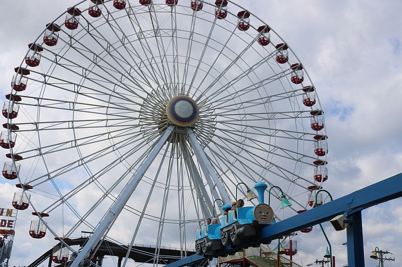 A monorail train rides by the landmark Ferris Wheel that towers 140 feet above the amusement park.