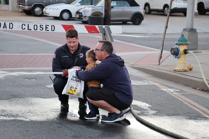 Brian Hill and his 3-year-old son, Robert, spray a fire hose with the assistance of a firefighter during the 2024 open house.