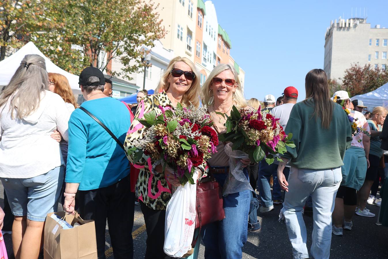 Friends Kathy Straube, left, and Karen Wuko, show off the bouquets of flowers they bought at the block party.