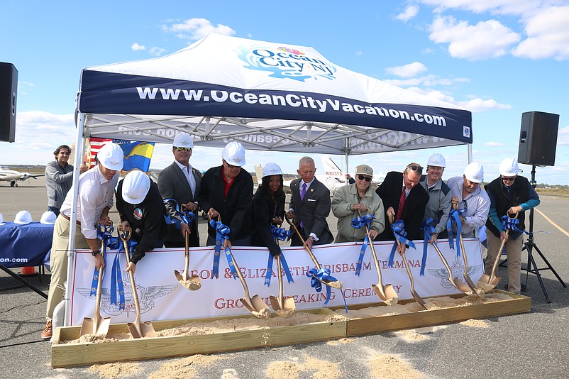 The airport groundbreaking ceremony includes dignitaries symbolically digging into the dirt.