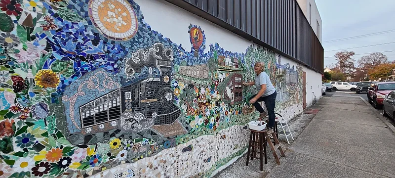 Local artist Roxanne Slemmer steps up to add a piece to her mosaic mural at Main and Ridge Streets in Lansdale on Wednesday, Oct. 30, 2024.