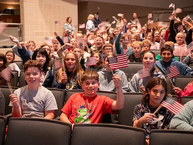 Sixth grade students wave American flags during the assembly. (Courtesy of David Thomas)