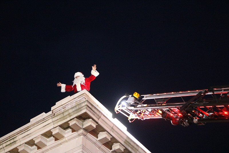 Santa waves to the crowd from the roof of City Hall while preparing to climb down the steps of an Ocean City Fire Department ladder truck.