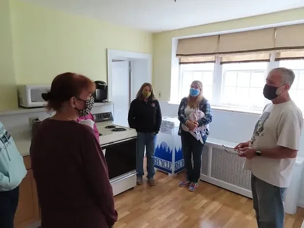 Code Blue shelter organizers Leslie Johnson, left front, and Mark Lanan, right front, speak to volunteers Julia Menzo, second from left, and Linda Rowland inside the kitchen area of the Code Blue shelter at Trinity Lutheran Church’s Luther Hall on Tuesday, Oct. 12 2021.