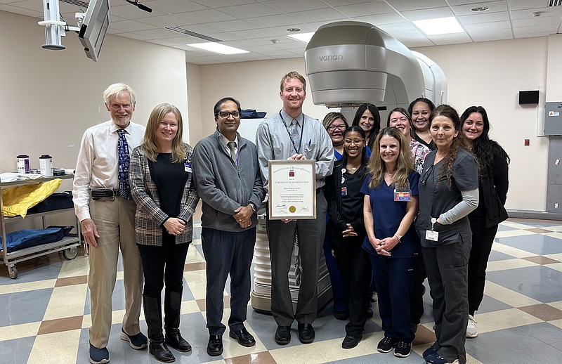 Physicians and staff of Shore Cancer Center's Radiation Oncology program display their American College of Radiation Oncology reaccreditation certificate, standing in front of the Varian TrueBeam linear accelerator.