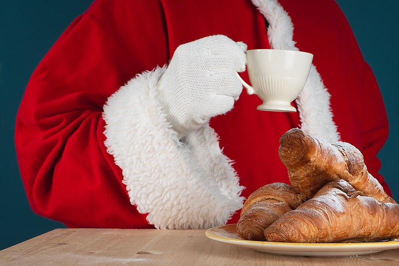 Santa Claus is holding a cup of coffee and eating gourmet croissants. Have a good Christmas and New Year's mood. Cozy at home or in a cafe with hot drinks.