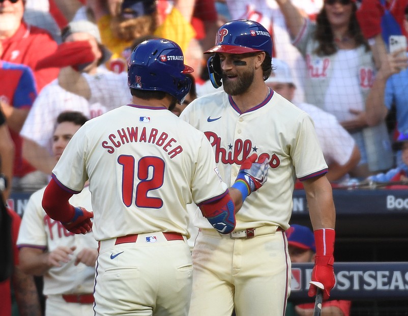 Oct 5, 2024; Philadelphia, PA, USA;  Philadelphia Phillies designated hitter Kyle Schwarber (12) celebrates with Philadelphia Phillies first baseman Bryce Harper (3) after a solo home run against the New York Mets in the first inning in game one of the NLDS for the 2024 MLB Playoffs at Citizens Bank Park. Mandatory Credit: Eric Hartline-Imagn Images