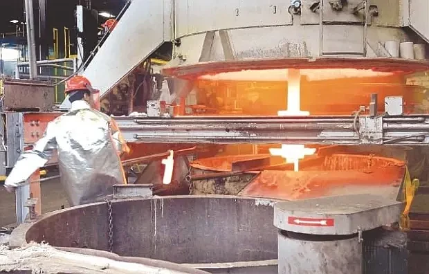 A worker in a production area at Rex Heat Treat in Lansdale removes a metal part following a quenching procedure. (Credit: MediaNewsGroup)