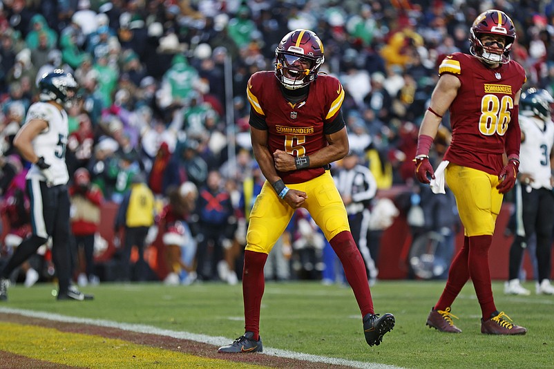 Dec 22, 2024; Landover, Maryland, USA; Washington Commanders quarterback Jayden Daniels (5) celebrates after throwing the game winning touchdown during the fourth quarter against the Philadelphia Eagles at Northwest Stadium. Mandatory Credit: Peter Casey-Imagn Images