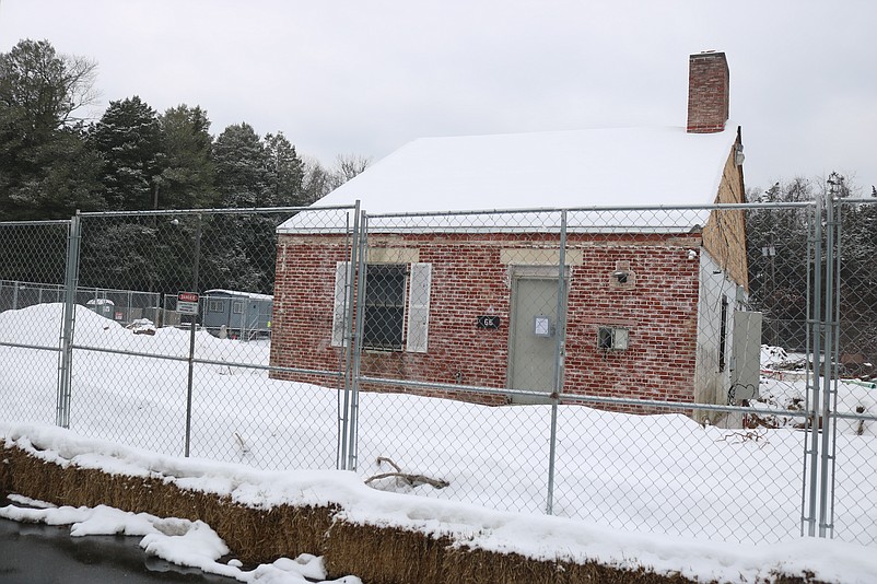 The building is surrounded by a chain-link fence for the construction project.