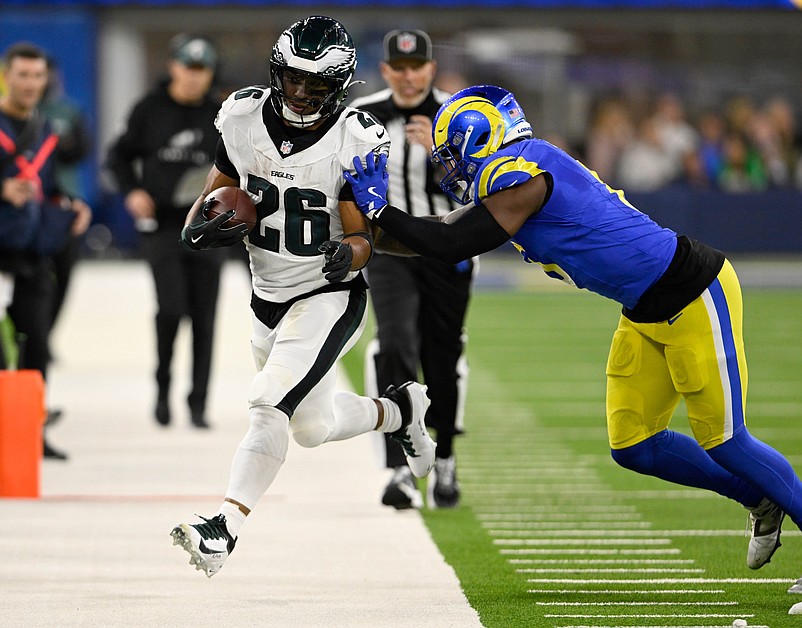 Nov 24, 2024; Inglewood, California, USA;  Philadelphia Eagles running back Saquon Barkley (26) gets pushed out-of-bounds by Los Angeles Rams linebacker Jared Verse (right) during the first half at SoFi Stadium. Mandatory Credit: Alex Gallardo-Imagn Images