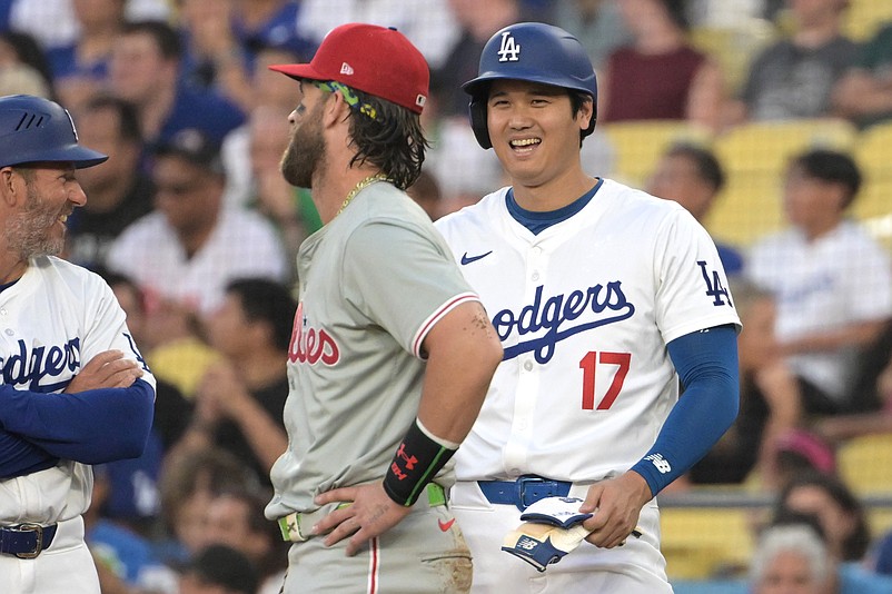 Aug 7, 2024; Los Angeles, California, USA;  Los Angeles Dodgers designated hitter Shohei Ohtani (17) laughs with Philadelphia Phillies first baseman Bryce Harper (3) as they wait for a replay in the first inning at Dodger Stadium. Mandatory Credit: Jayne Kamin-Oncea-USA TODAY Sports