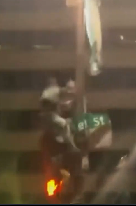 Screenshot of an 18-year-old falling off a light pole at 15th and Market Street following the Eagles win on Sunday. (@TheMagaHulk on X)