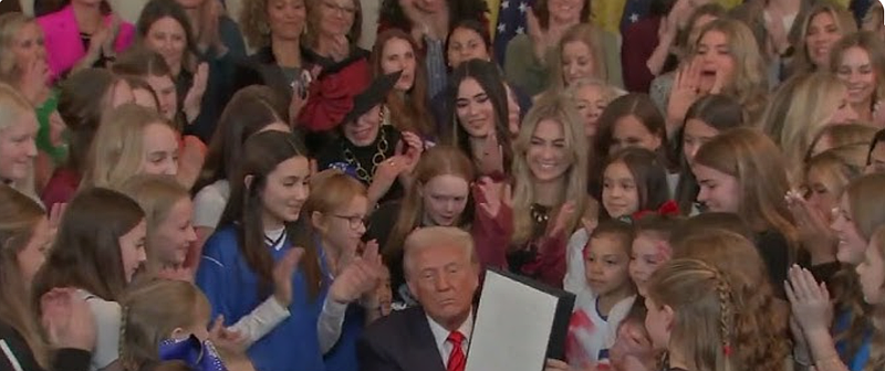 President Trump, surrounded by dozens of young, female, athletes, signs an executive order on Feb. 5, 2025, declaring that biological males can not participate in women's sports. (Credit: YouTube)