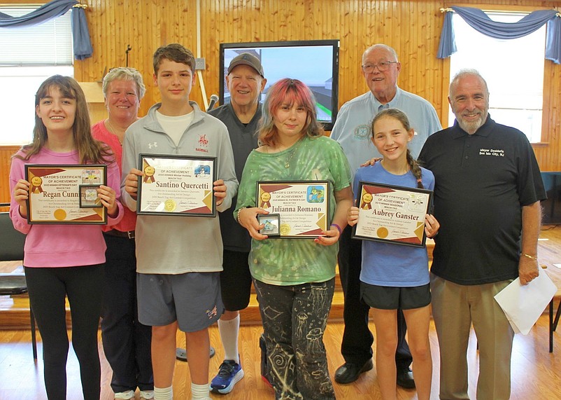 Sea Isle City officials join with the Beach Tag Art Contest winners, from left, holding plaques, Regan Cunningham, Santino Quercetti, Julianna Romano and Aubrey Ganster. (Courtesy of Sea Isle City)