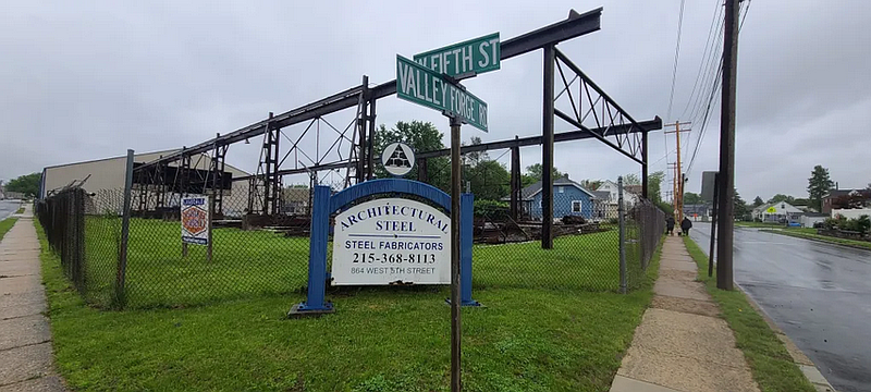 A family walks past a steel fabrication business on the corner of Valley Forge Road and West Fifth Street in Lansdale on Tuesday, May 13, 2025.