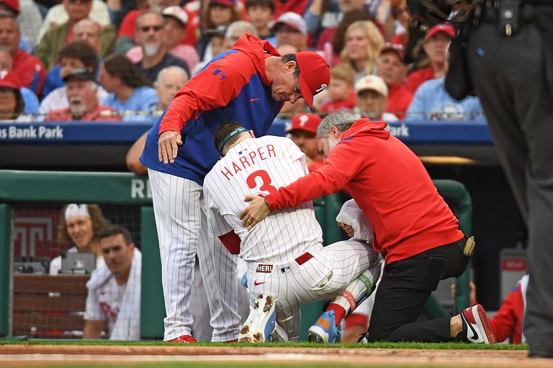 May 27, 2025; Philadelphia, Pennsylvania, USA; Philadelphia Phillies first base Bryce Harper (3) is looked at by Philadelphia Phillies manager Rob Thomson (59) and  trainer Joe Rauch after being hit by a pitch during the first inning against the Atlanta Braves at Citizens Bank Park. Mandatory Credit: Eric Hartline-Imagn Images
