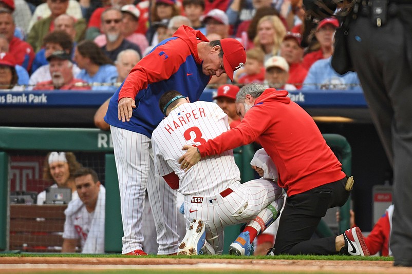 May 27, 2025; Philadelphia, Pennsylvania, USA; Philadelphia Phillies first base Bryce Harper (3) is looked at by Philadelphia Phillies manager Rob Thomson (59) and  trainer Joe Rauch after being hit by a pitch during the first inning against the Atlanta Braves at Citizens Bank Park. Mandatory Credit: Eric Hartline-Imagn Images