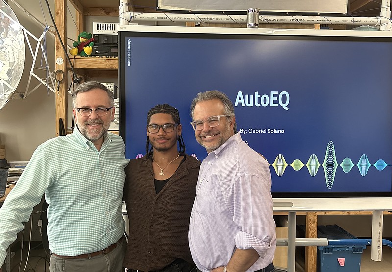Gabe Solano (center), 2025 Gates Scholarship recipient, presents his AutoEQ prototype in the Science Leadership Academy's engineering lab. His engineering teacher, John Kamal (left), and SLA principal and founder, Chris Lahmann (right), attended the presentation to support Solano, alongside his classmates. (Credit: Kate Jackson)