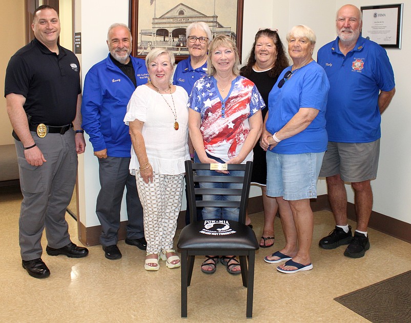 Sea Isle City officials and members of the VFW Post 1963 Auxiliary, including President Peggy Moore, center, stand behind the POW-MIA Chair of Honor on display in City Hall. (Photo courtesy of Sea Isle City)