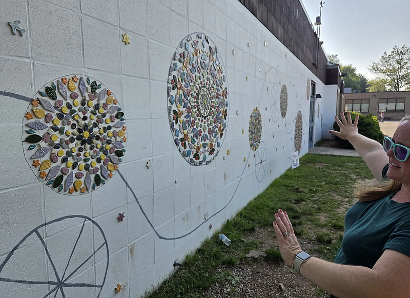 Parent Megan Forman shows the size of a 500-square-foot wall to be covered by a mosaic mural at North Wales Elementary School on Wednesday, June 4, 2025.