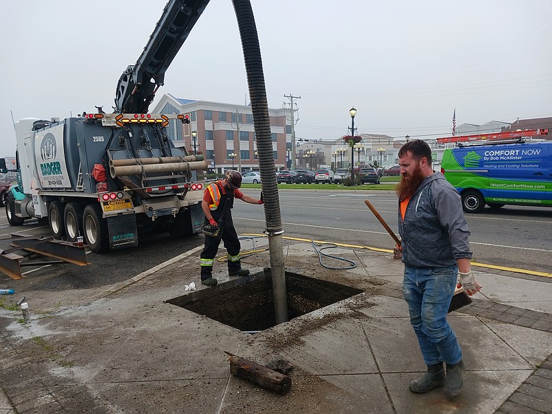 Workers cut a hole in the sidewalk for the base of the new sign at the intersection of JFK Boulevard and Central Avenue.