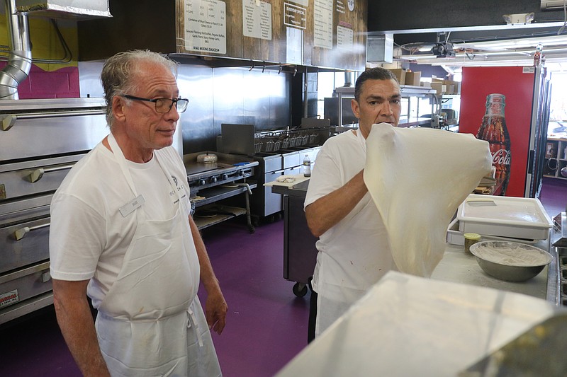 Bill Micchelli, left, operator of the new OC Pizza Co. shop at the former Wonderland Pier property, watches Kevin Gilbert make a pie.