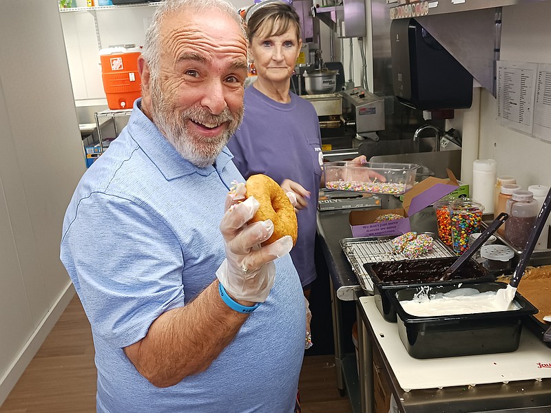 Mayor Leonard Desiderio, with donut-making guidance from Joanne Jenkins, shows off one of his creations.