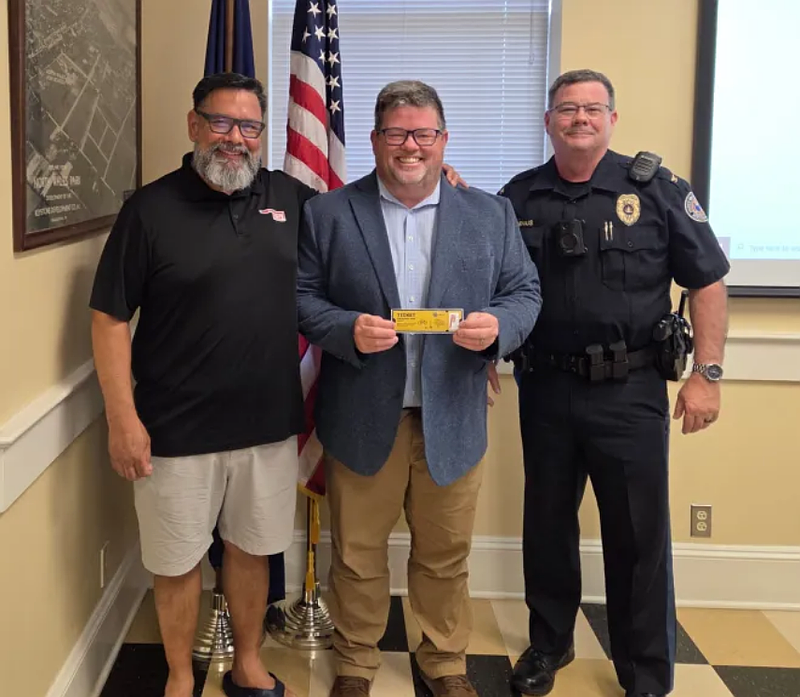 Bob Zimmerman of Soul Brothers Meats, North Wales Mayor Neil McDevitt, and police Chief Dave Erenius pose with a ‘ticket’ for a free snack stick at Soul Brothers for residents spotted by police wearing helmets in town, at the borough council meeting on Tuesday, June 24, 2025.
