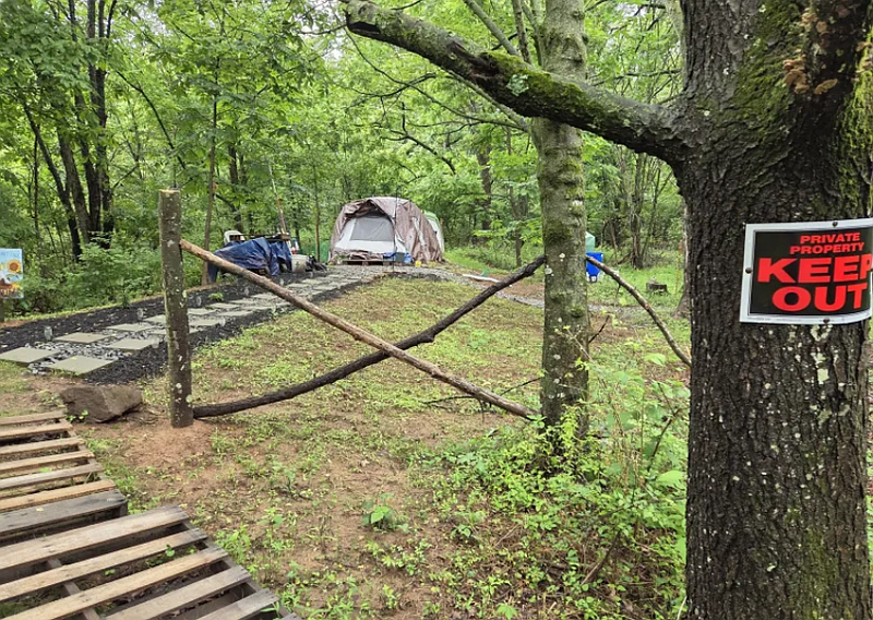 A ‘Keep Out’ sign posted on a tree warns visitors to stay away from an encampment of tents in Stony Creek Park in Lansdale on Tuesday, June 10, 2025.