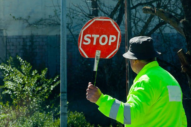 A crossing guard holding up traffic. (Credit: IStock by Getty Images)