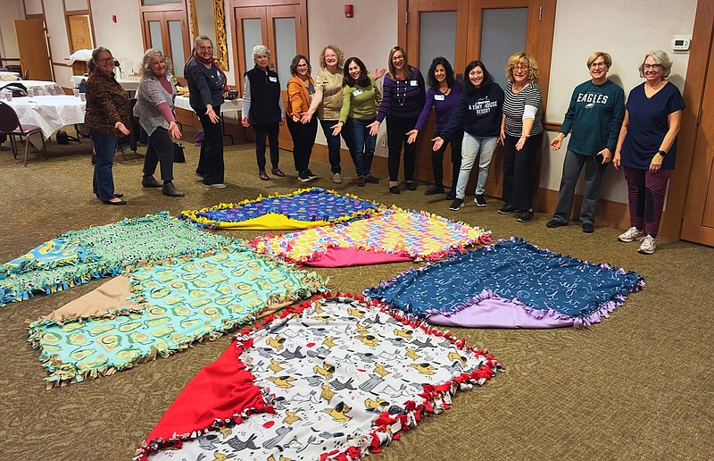 Members of Women of Shir Ami pose with the fleece tie blankets that they made for NOVA clients.  In addition to offering clients physical warmth, the blankets provide emotional comfort, reminding clients that they are cared for and supported as they engage in counseling to work through their trauma. (Credit: Women of Shir Ami)