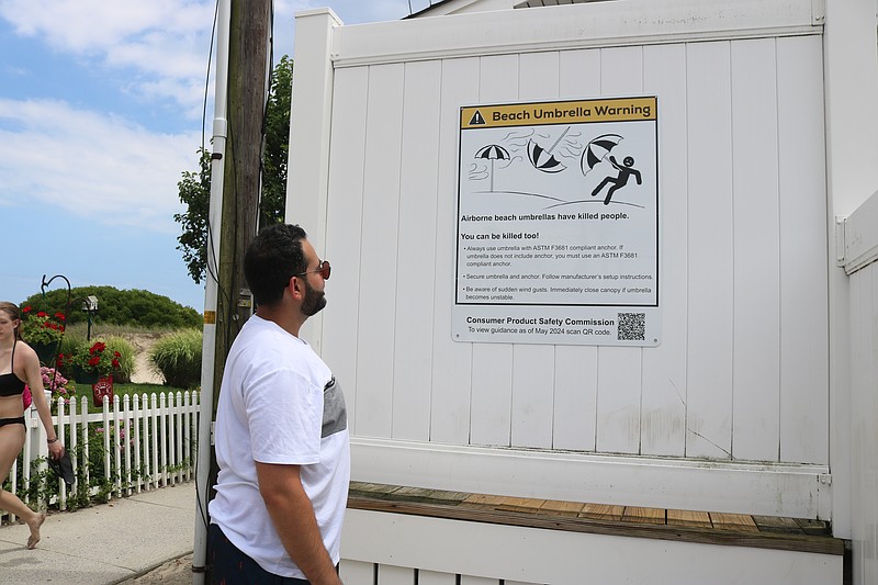Peter Estephan, a vacationer from Scranton, Pa., reads the umbrella warning sign posted at the entrance to the 34th Street beach.