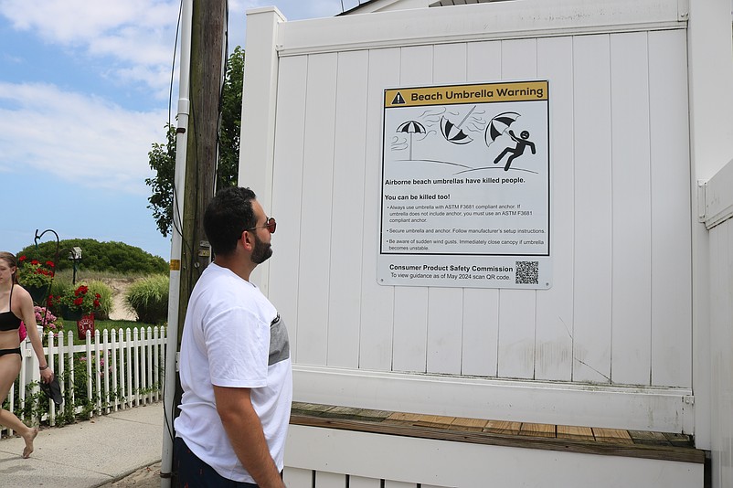 Peter Estephan, a vacationer from Scranton, Pa., reads the umbrella warning sign posted at the entrance to the 34th Street beach.