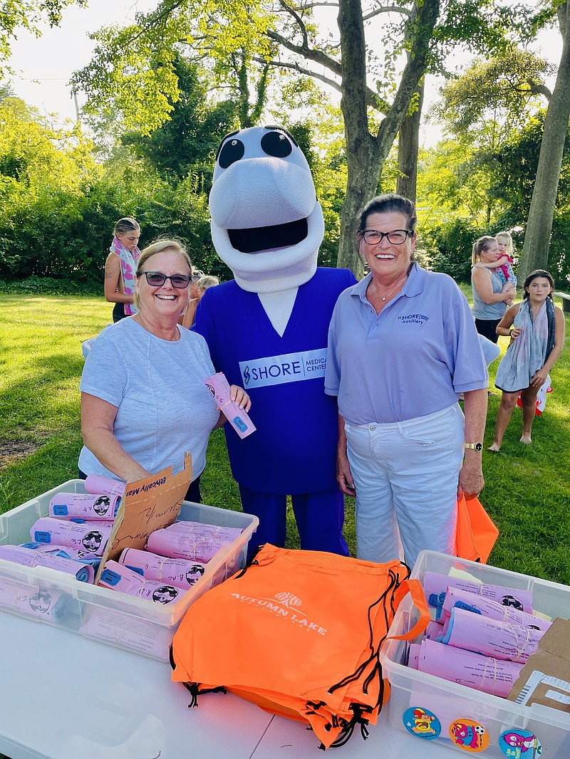 PROVIDED/Shore Auxiliary members Brenda Martello and Diane Conover pose with Shore ambassador Fin the Dolphin as they hand out T-shirts at the Carol Schiavo Kids Swim for Health awards picnic July 24.