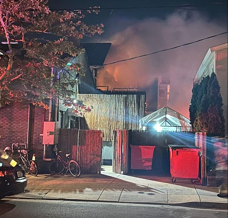 Flames and smoke shoot out from the second floor of the house at 104 Atlantic Ave., next to the Island Grill.