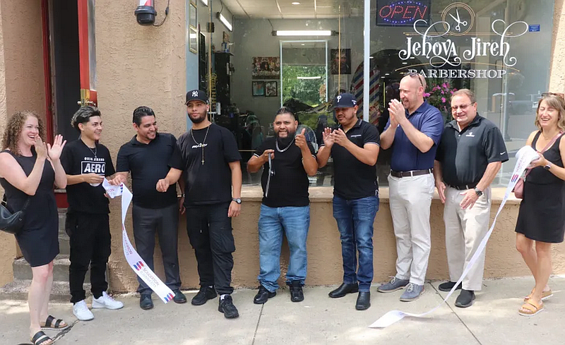 Owner Freddy Madrid cuts the ribbon at the grand opening celebration of Jehova Jireh Barbershop in Souderton.