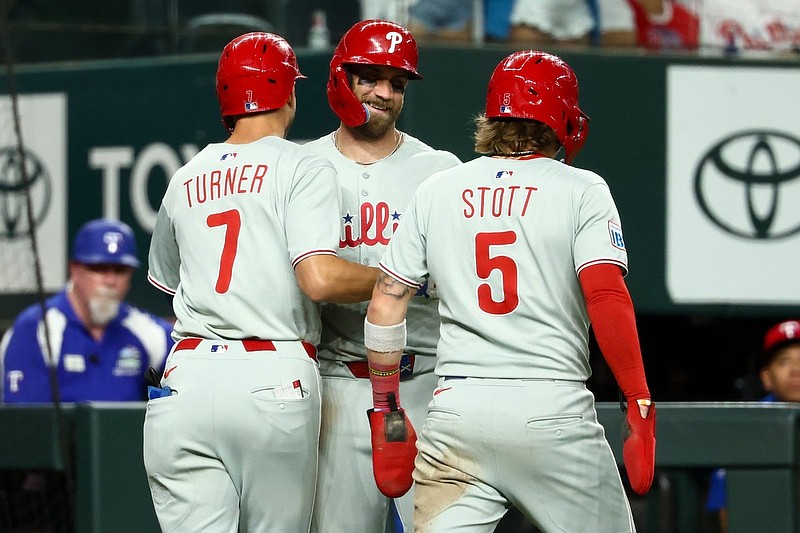 Aug 8, 2025; Arlington, Texas, USA;  Philadelphia Phillies shortstop Trea Turner (7) celebrates with Philadelphia Phillies second baseman Bryson Stott (5) and Philadelphia Phillies first baseman Bryce Harper (3) after hitting a three-run home run during the ninth inning against the Texas Rangers at Globe Life Field. Mandatory Credit: Kevin Jairaj-Imagn Images