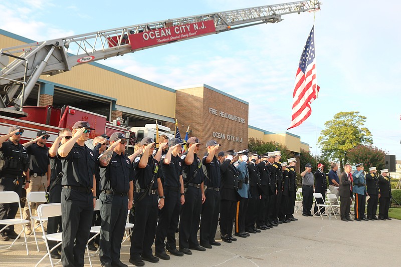 Ocean City firefighters and police officers salute while standing at attention during the start of the 9/11 ceremony.