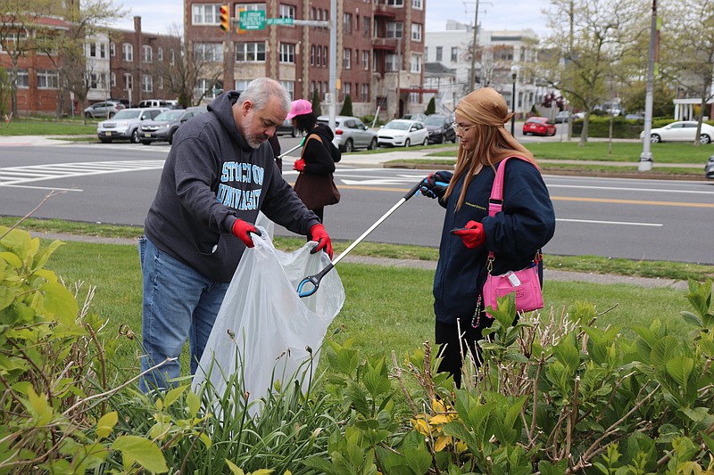 Stockton University President Joe Bertolino and Kyra Vasiliou clean up around the Atlantic City campus.