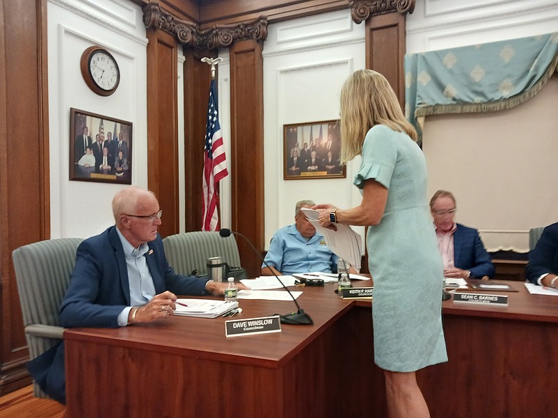 City Solicitor Dorothy McCrosson hands out copies of the proposed resolution to the Council members.