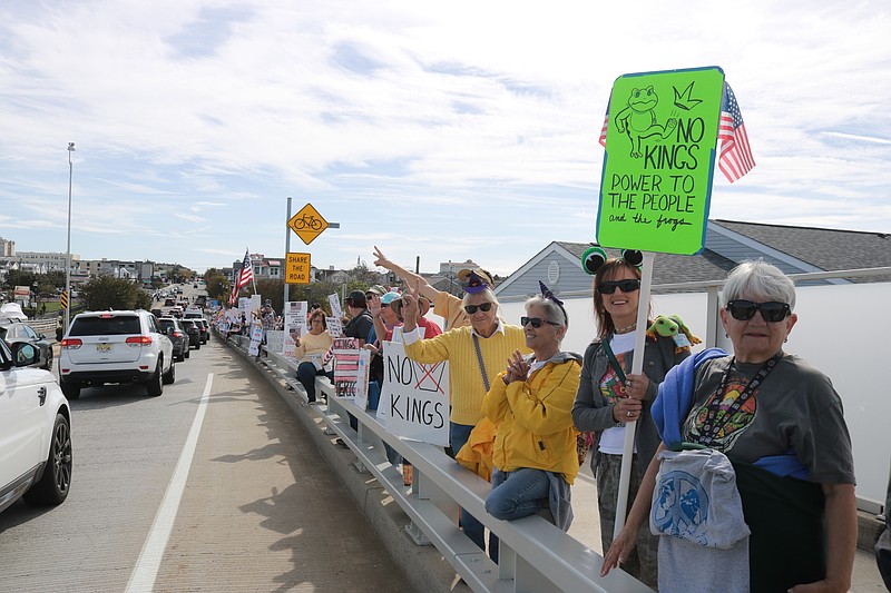 Protesters hold their signs and exchange waves with motorists driving into Ocean City during the No Kings rally.