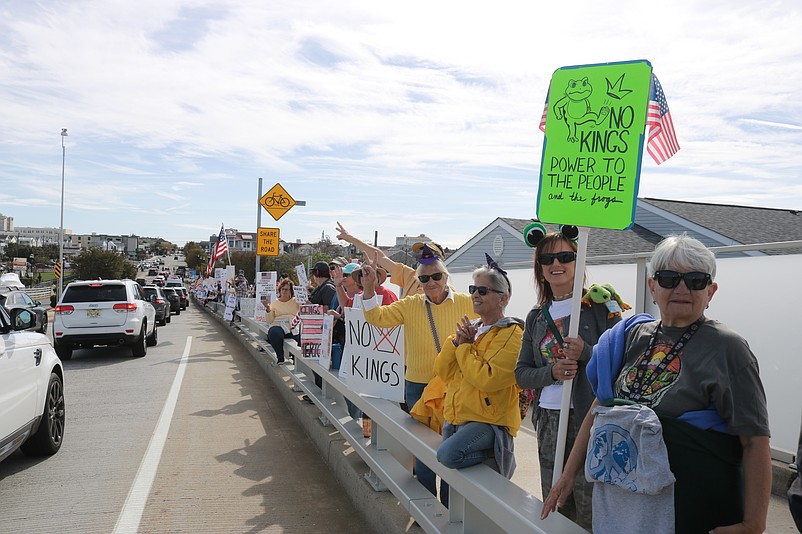 Protesters hold their signs and exchange waves with motorists driving into Ocean City during the No Kings rally.