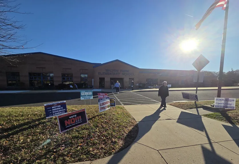 Voters walk past campaign signs for dueling slates of township and school board candidates at Walton Farm Elementary School in Towamencin on Tuesday, Nov. 4, 2025.
