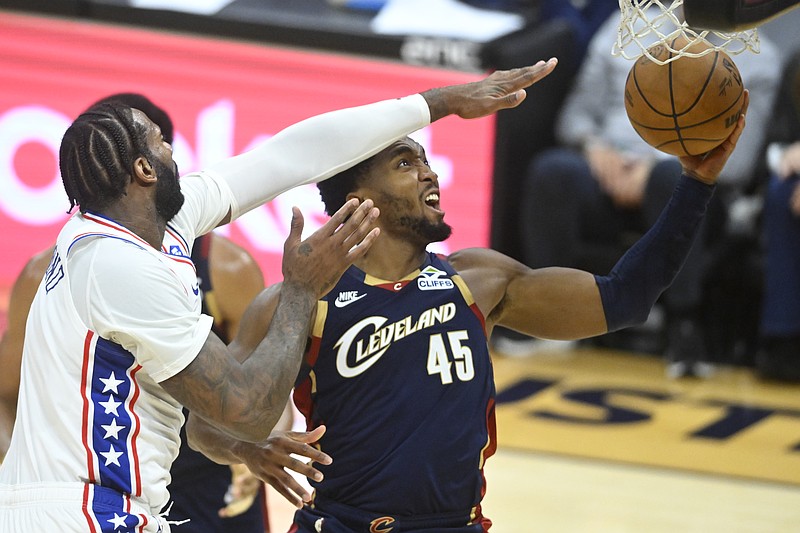 Nov 5, 2025; Cleveland, Ohio, USA; Cleveland Cavaliers guard Donovan Mitchell (45) drives to the basket beside Philadelphia 76ers center Andre Drummond (1) in the fourth quarter at Rocket Arena. Mandatory Credit: David Richard-Imagn Images