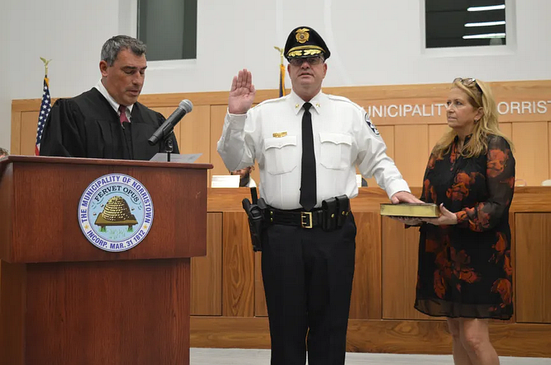 Magisterial District Judge Edward Levine, left swears in Norristown Police Chief Mike Trail during a Nov. 5, 2025 council meeting. Trail is joined by his wife, Grace.