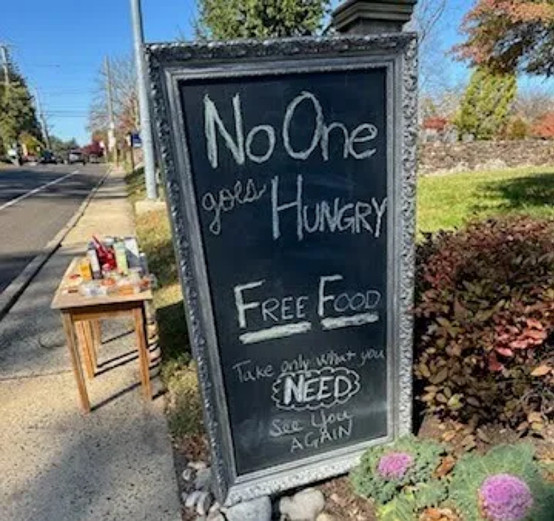 A sign on Main Street in North Wales reads ‘No one goes hungry: Free Food’ next to a table where passersby can leave or take donations. (Photo courtesy of Meghan Surdenas)