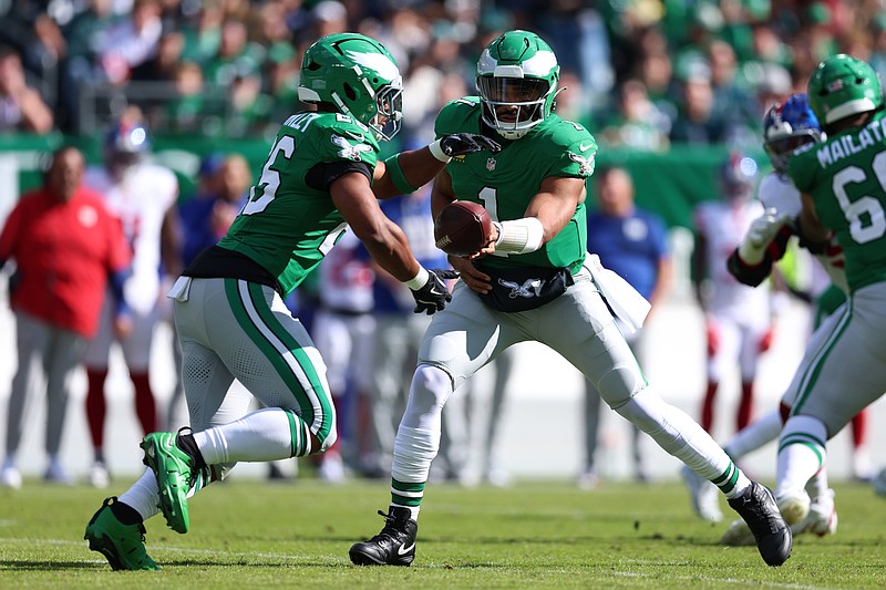 Oct 26, 2025; Philadelphia, Pennsylvania, USA; Philadelphia Eagles quarterback Jalen Hurts (1) hands the ball off to running back Saquon Barkley (26) in the first quarter against the New York Giants at Lincoln Financial Field. Mandatory Credit: Bill Streicher-Imagn Images